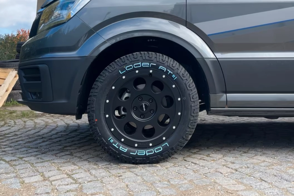 Schwarze Offroad-Felge an einem grauen Fahrzeug montiert.