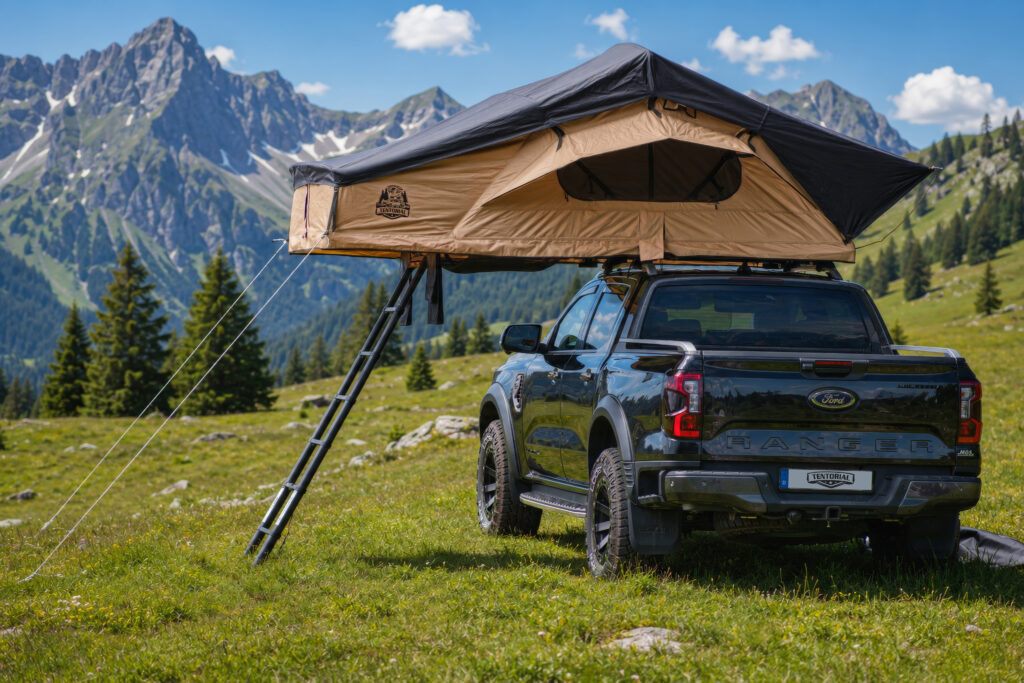 Auf einer Bergwiese steht ein Ford Ranger mit TENTORIAL Dachzelt Montana in Sand und schwarzer Softshell.