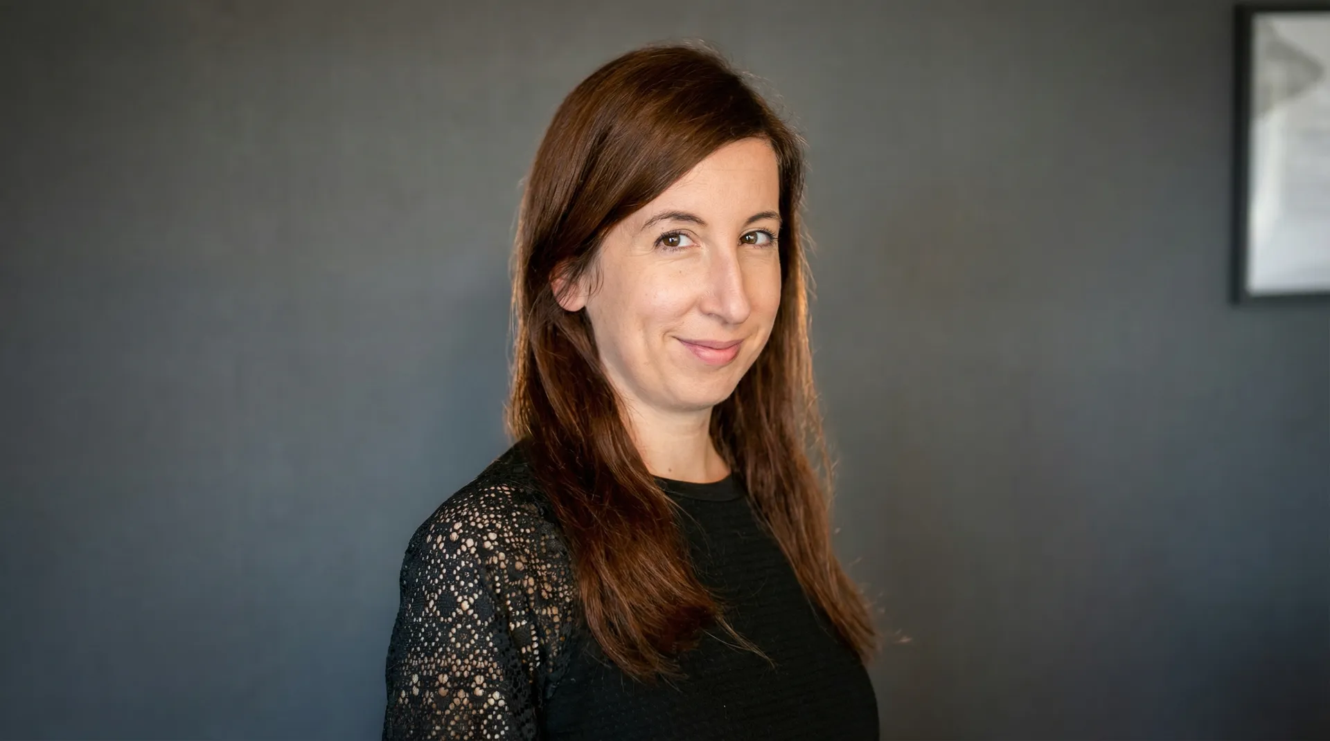 Frau mit langen braunen Haaren in schwarzem Spitzenoberteil.