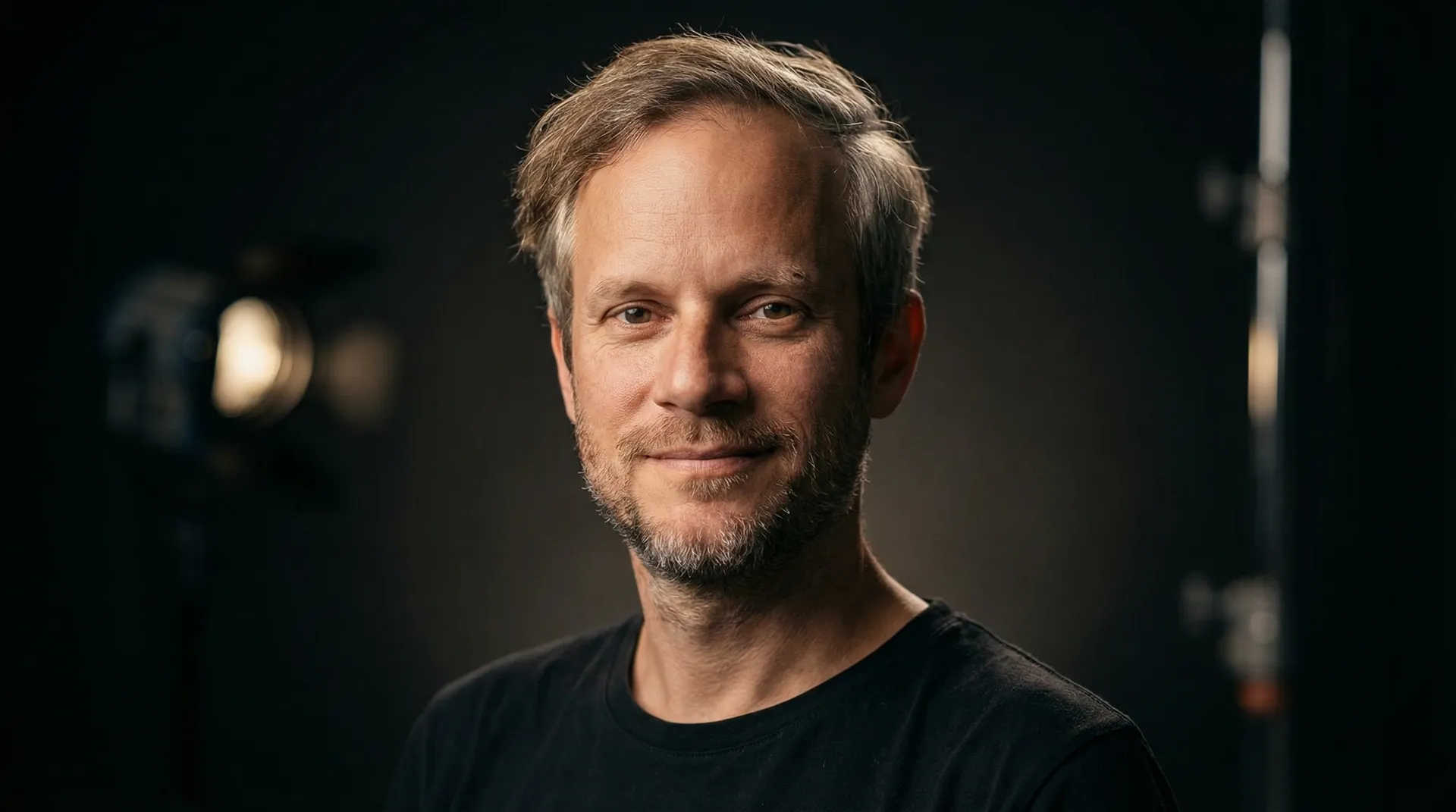 Mann mit blonden Haaren und Bart in schwarzem T-Shirt.